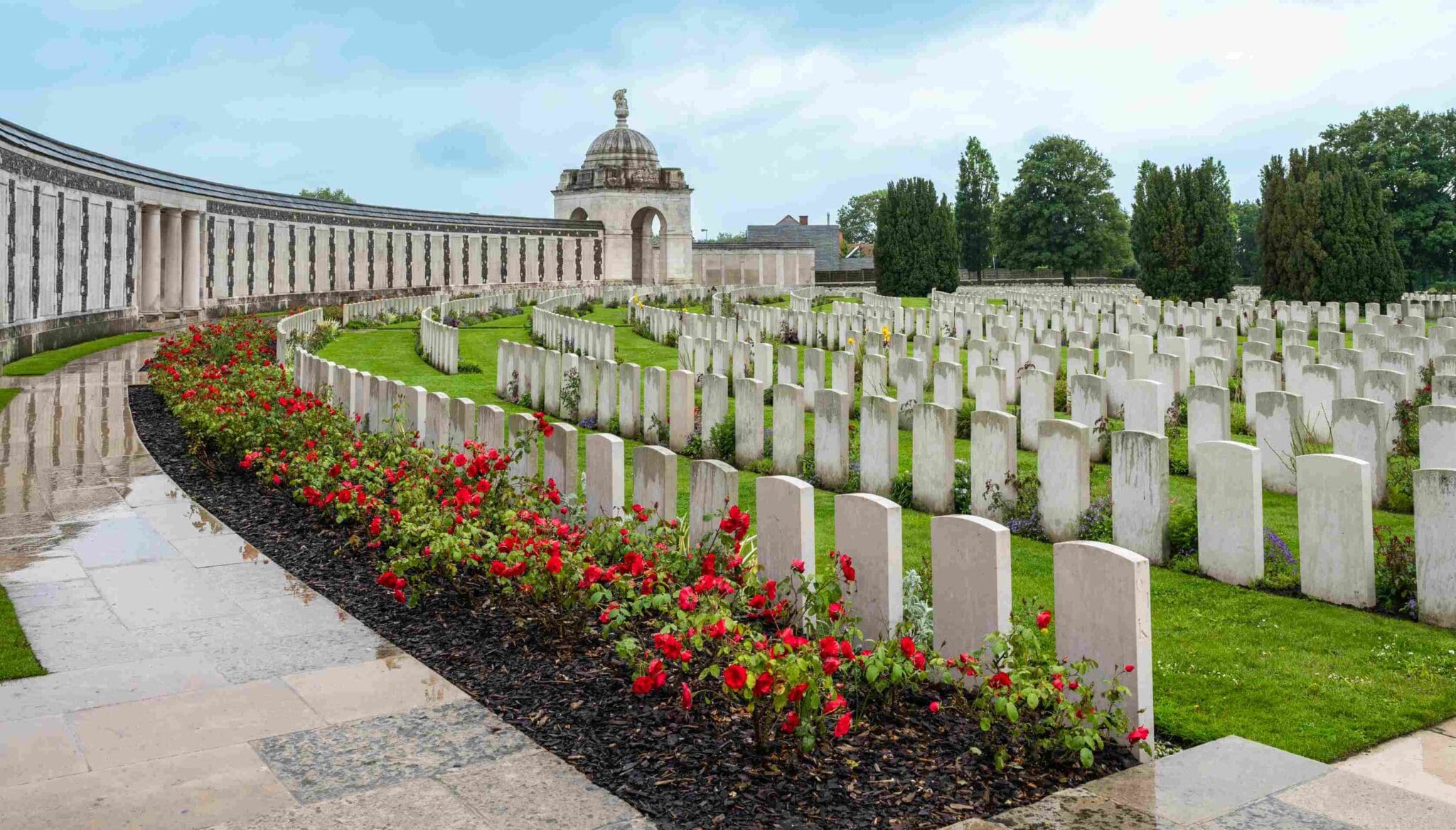 War cemetery with headstones and red flowers.